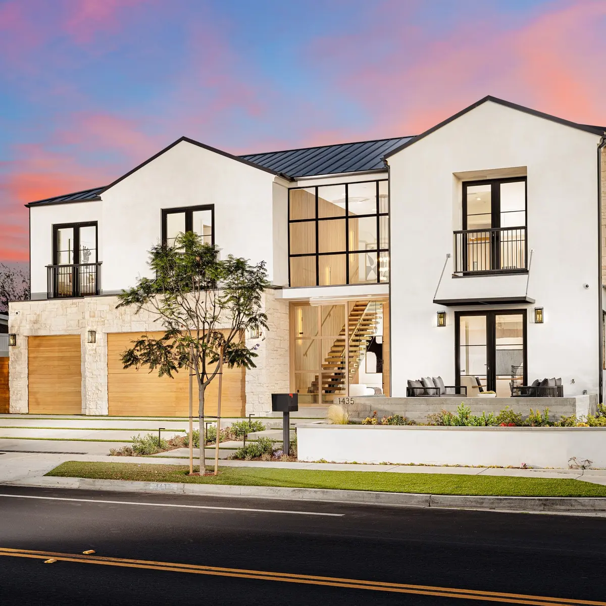 Modern farmhouse at dusk with a lit interior and pink sky, Dover Shores, Newport Beach